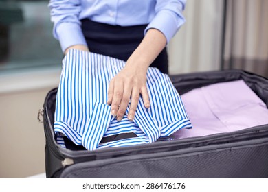 Business, Trip, Luggage And People Concept - Close Up Of Businesswoman Packing Clothes Into Travel Bag