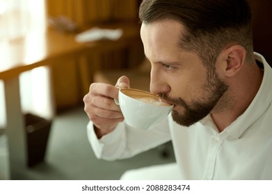 Business trip and people concept. Close-up portrait of attractive charming handsome successful European bearded businessman drinking freshly brewed coffee at hotel room, for perfect start of the day - Powered by Shutterstock