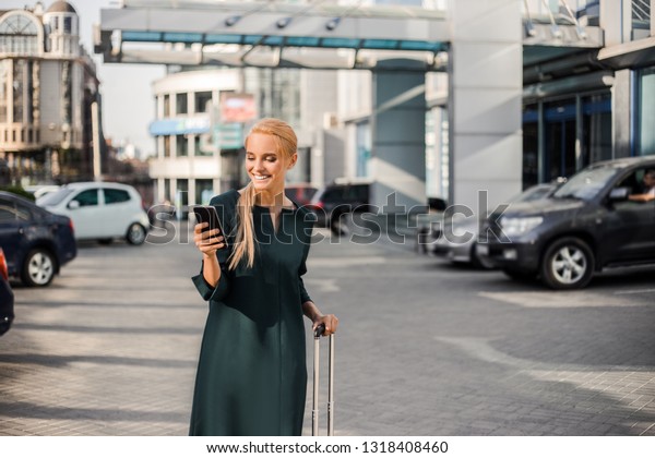 Business trip, traveling for\
work, ofissial style successful woman walking urban Airport,\
waiting for vip car rental service and searching internet on cell\
phone. 