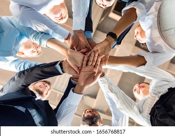 Business Unity And Teambuilding. United Colleagues Standing In Circle Holding Hands Together In Modern Office. Bottom View