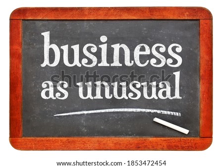 business as unusual blackboard sign - white chalk text on a vintage slate blackboard, new normal and coronavirus pandemic concept