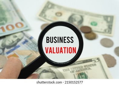 Business Valuation.Magnifying glass showing the words.Background of banknotes and coins.basic concepts of finance.Business theme.Financial terms.