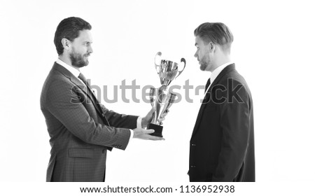 Business victory and success concept. Businessman with surprised face receives golden prize. Awarded best worker receives trophy on white background. Partners celebrate winning competition.