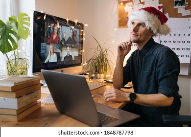 Business Video Conferencing. Young Man Having Video Call Via Computer In The Home Office. Virtual Christmas House Party. Online Team Meeting Video Conference Calling From Home. Man Wearing Santa Hat