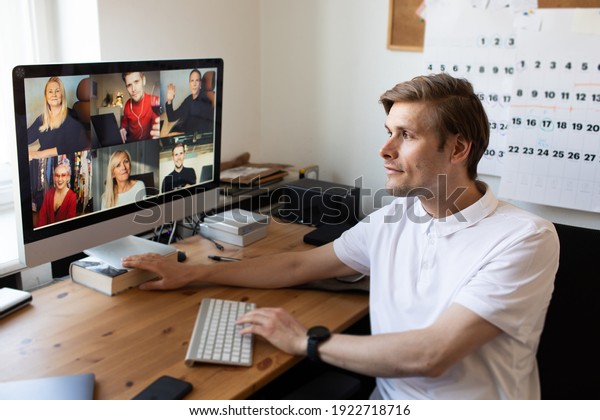 Business\
video conferencing. Young man having video call via computer in the\
home office. Multiethnic business team. Virtual house party. Online\
team meeting video conference calling from\
home