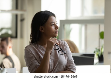 Business vision. Pensive thoughtful millennial biracial female worker employee standing at office workplace taking short break in work looking at distance planning future career, creating new ideas - Shutterstock ID 1849648669
