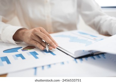 Business woman accountant working audit inspect calculating expense annual financial report balance sheet statement, doing finance making notes checking document and data analysis profit graph - Powered by Shutterstock