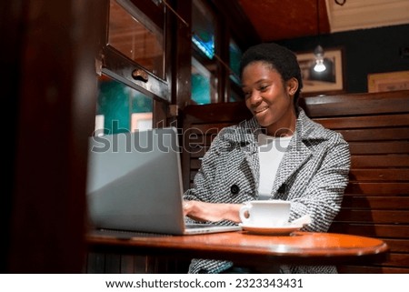 Business woman of African ethnicity in a coffee shop, break time finance woman with a computer