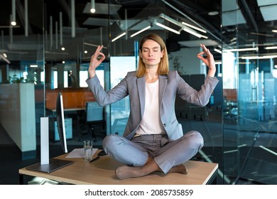 Business woman alone sitting at desk in her office, female employee meditating in lotus position - Powered by Shutterstock