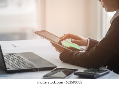 A business woman analyzing investment charts at workplace and using laptop and touch tablet. - Shutterstock ID 682598035