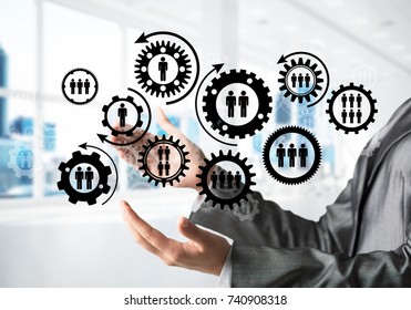 Business woman in black suit keeping black social gear icons in hands with office view on background. Mixed media. - Shutterstock ID 740908318