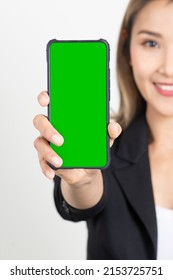 Business Woman In Black Suit Showing Green Screen On Display Of Smartphone On White Background. Half Face Of Business Woman Holding Smartphone With Green Display. 