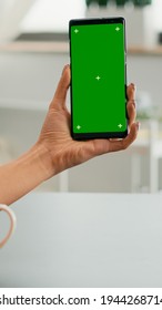 Business Woman Browsing On Internet Using Mock Up Green Screen Chroma Key Smartphone Sitting At Office Desk. Freelancer Swiping Online Information For Social Media Project Using Isolated Device