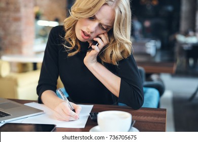 business woman is busy negotiating by phone, writes in documents                               