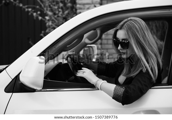 Business woman in a car, auto lady concept.\
Stylish lady in black jacket and\
glasses