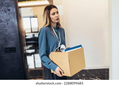 Business woman carrying packing up all his personal belongings and files into a brown cardboard box to resignation in modern office, resign concept.