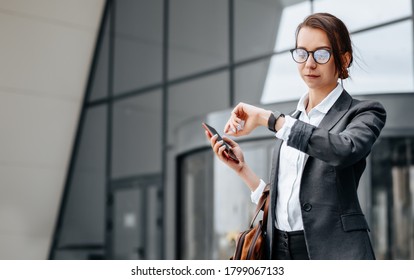 A business woman checks the time in the city during a working day waiting for a meeting. Discipline and timing. An employee goes towards a corporate meeting. - Shutterstock ID 1799067133