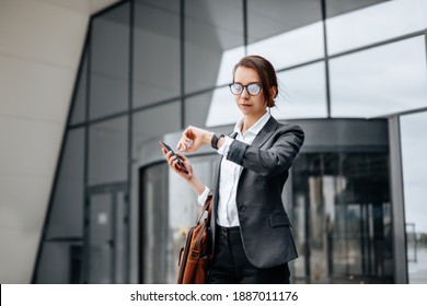 A business woman checks the time in the city during a working day waiting for a meeting. Discipline and timing. An employee goes towards a corporate meeting. - Shutterstock ID 1887011176