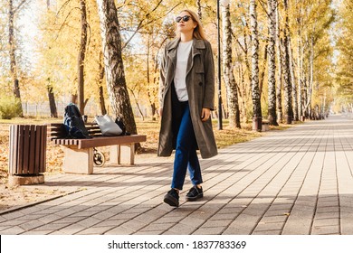 Business woman in coat walk in the autumn park, bottom view. Autumn park, sunny day.
