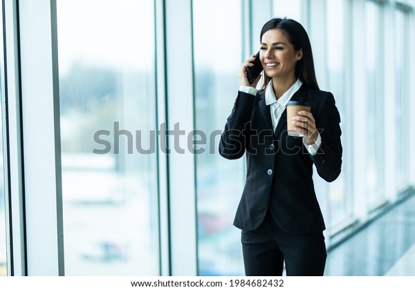 Business woman with coffee and talking on the\
phone near office