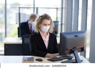 Business woman with curly blonde hair wearing a mask sitting in office, Concept,contagious disease, covid 19, coronavirus.