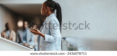 Business woman delivers a speech to colleagues. Woman expressing expertise and leadership in a modern corporate setting, aiming to engage with her audience during a professional meeting.