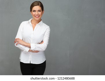 Business woman dressed white shirt standing with crossed arms in front of grey wall back.