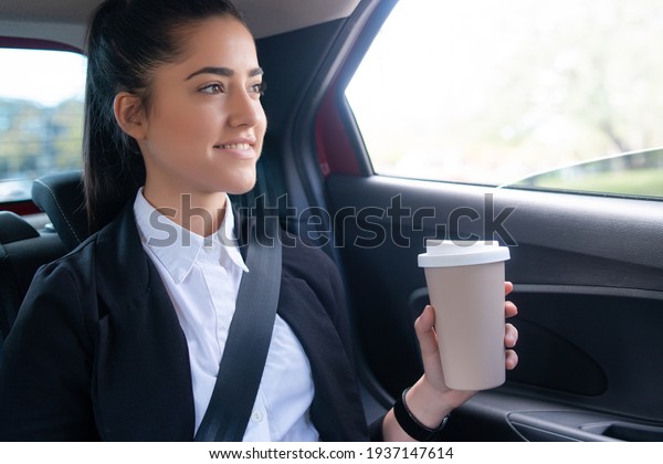 Business woman drinking\
coffee in car.