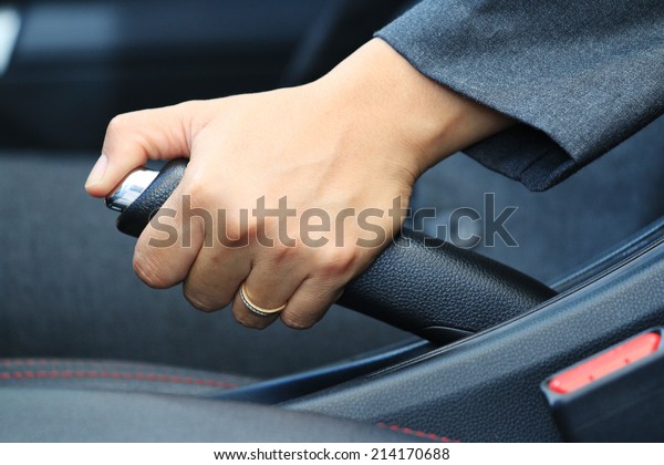 Business woman driver pulling the hand brake\
in car, in car\
background.