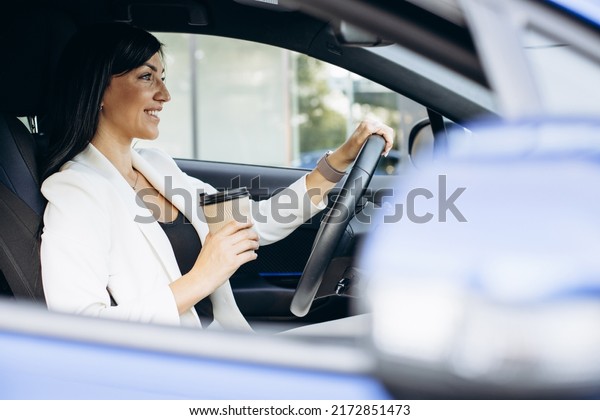 Business woman\
driving in car and drinking\
coffee