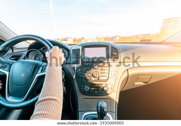 Business woman driving car. Travel car trip on road\
at sunset. Happy young woman have fun ride inside vehicle in winter\
sunny day