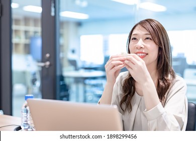 Business Woman Eating A Sandwich At The Office At Lunch Time