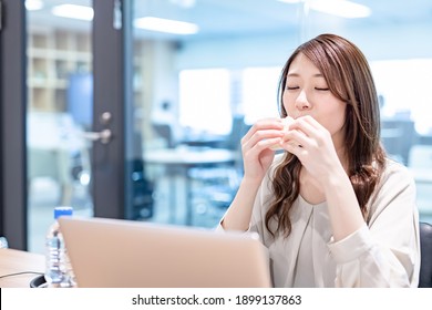 Business Woman Eating A Sandwich At The Office At Lunch Time