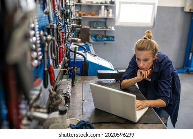 Business woman at a factory. Craftswoman working using a laptop in the garage. Mechanic using laptop at the repair garage. Young female mechanic with laptop. Business woman at a factory. - Powered by Shutterstock