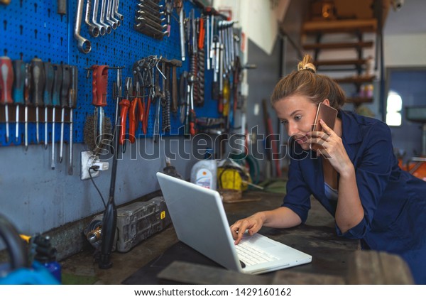 Business woman at a factory. Craftswoman working using a\
laptop in the garage. Mechanic using laptop at the repair garage.\
Young female mechanic with laptop. Business woman at a factory.\
