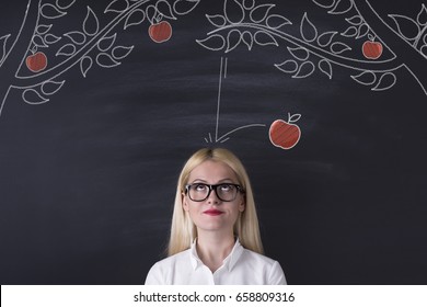 Business woman and falling apple on the blackboard