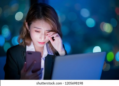 business woman feel tired and use phone at night