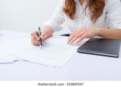 Business woman filling information on document.
