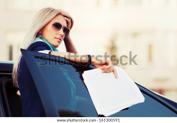 Business woman\
with financial papers at the\
car