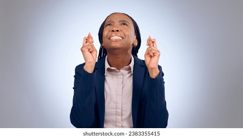 Business woman, fingers crossed and hope in studio for luck, thinking of wish or waiting for announcement on grey background. Nervous african worker, hand emoji or anxiety while praying for good news - Powered by Shutterstock