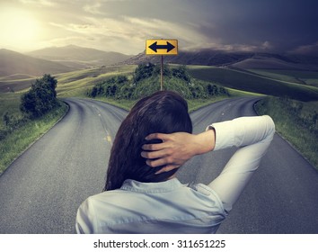 business woman in front of two roads thinking deciding hoping for best taking chance