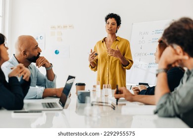 Business woman giving a speech during a boardroom meeting. Professional woman having a discussion with her colleagues in an office. Female project manager leading her team.