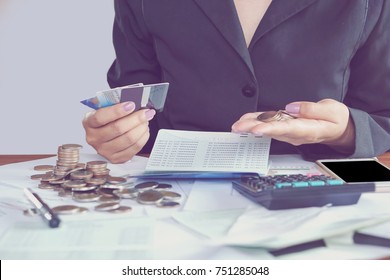  business woman hand calculating her monthly expenses during tax season with coins, calculator, credit card and account bank, idea for dept collection background 