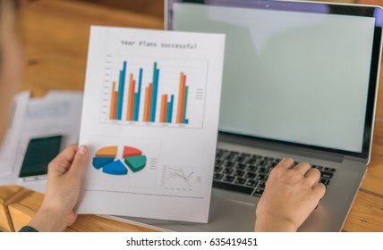 Business woman hand with Financial charts and laptop on the table
