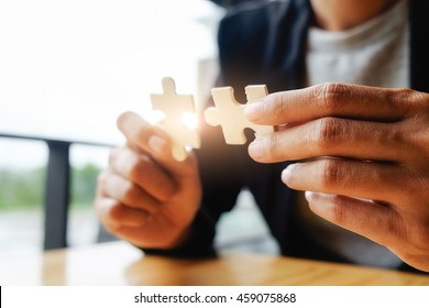 Business woman hands connecting jigsaw puzzle. Business solutions, success and strategy concept. Businessman concept. Close up photo with selective focus.

