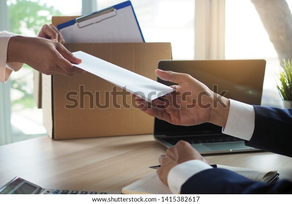 The business\
woman has a brown cardboard box next to her body and sends a letter\
of resignation to the executive. Include about resignation, job\
placement and vacancies.   