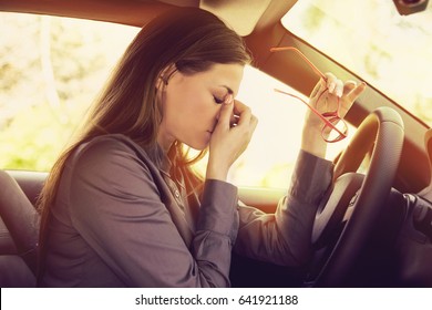 Business woman having headache taking off her glasses has to make a stop after driving car in traffic jam on rush hour. Exhausted, overworked driver concept.