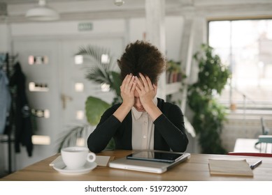 Business Woman Having Headache While Working Using Laptop Computer. Stressed And Depressed Girl Touching Her Head, Feeling Pain While Sitting At Wooden Table At Cafe. Work Failure Concept

