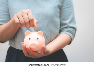 Geschäftsfrau hält Sparschwein und Münze mit Betonmauer für das Finanz- und Spargeldkonzept.