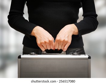 Business woman holding an aluminum briefcase and preparing for important negotiations and deals. Money and documents in safe hands of office worker.